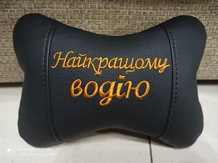 Чорна подушка для підголовка з вишивкою на українській мові.