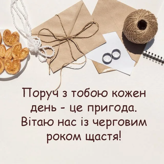 Весільна вітальна картка з кільцями та українським привітанням.