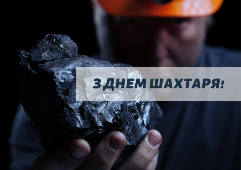 Шахтар тримає камінь вугілля на темному фоні.