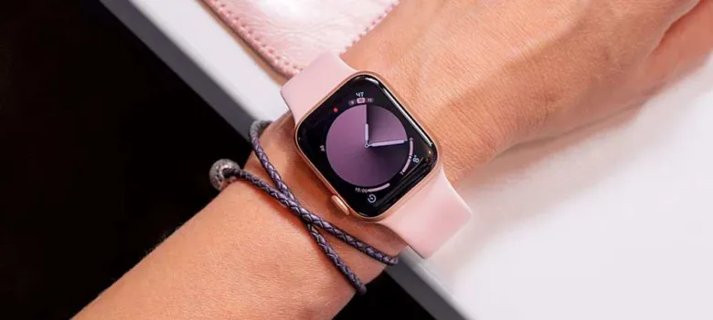 Чоловік носить рожевий годинник Apple Watch на руці.