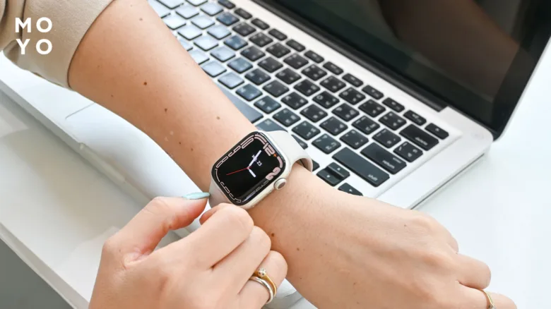 Чоловік носить годинник Apple Watch біля ноутбука