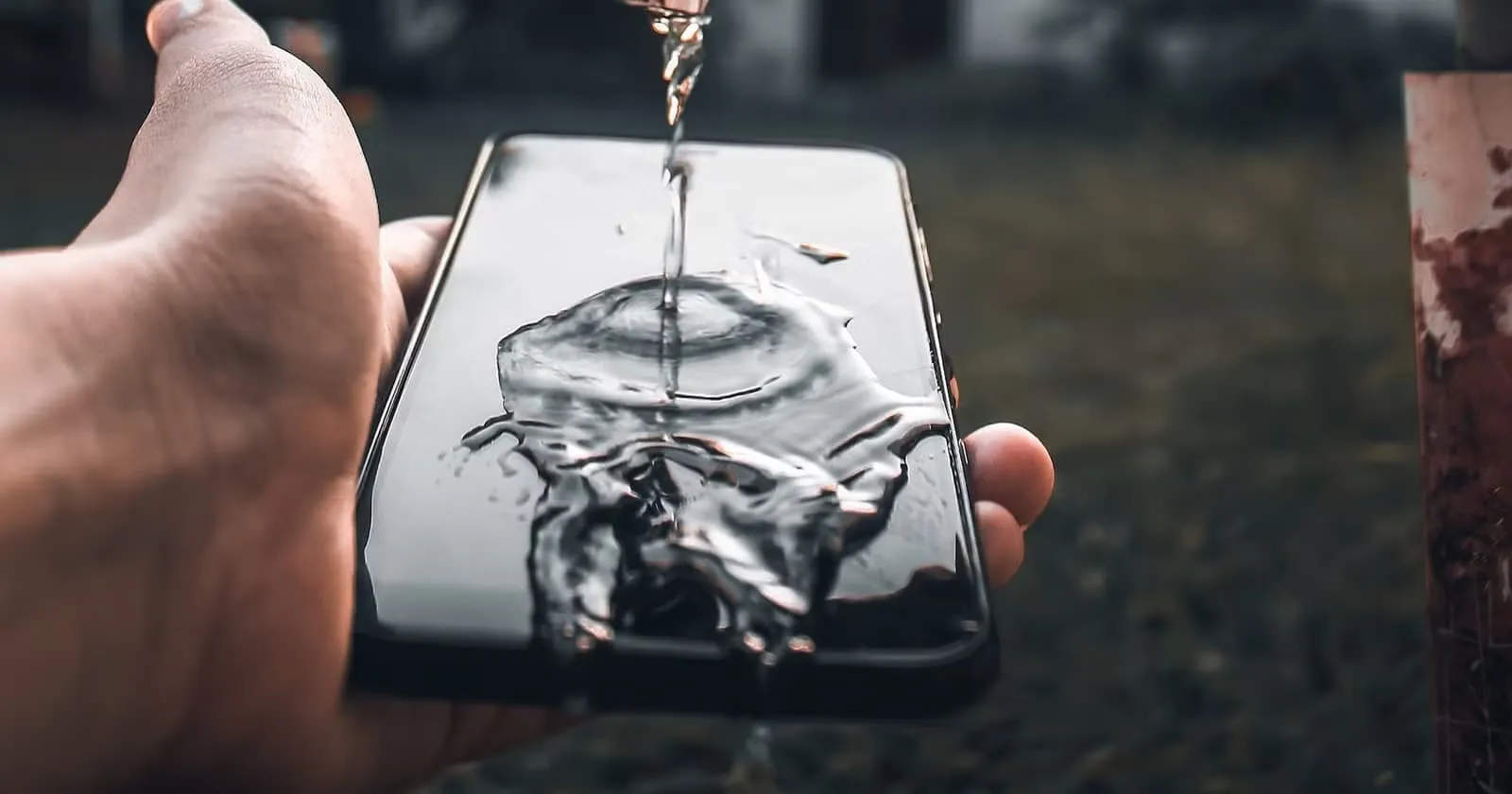 Вода ллється на чорний корпус смартфона.