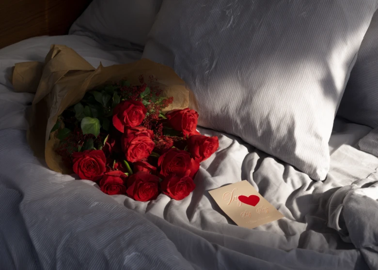 Квіти та листівка з написом Love на ліжку.