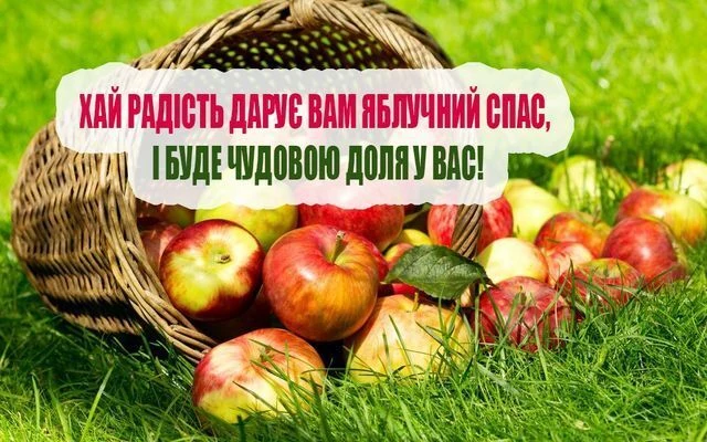 Корзина з яблуками на траві та привітання до Яблучного Спасу.
